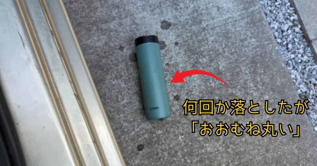 コンクリートの地面に置かれた緑色の水筒。