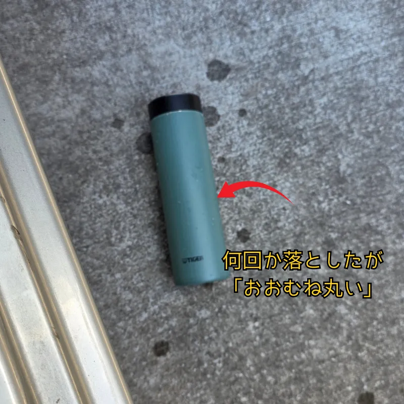 コンクリートの地面に落とした緑色の水筒。