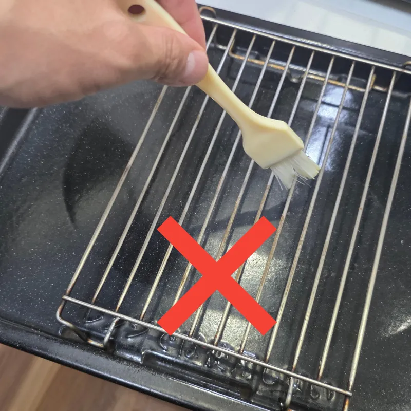天板にセットした網にハケで油を塗っている誤った方法。