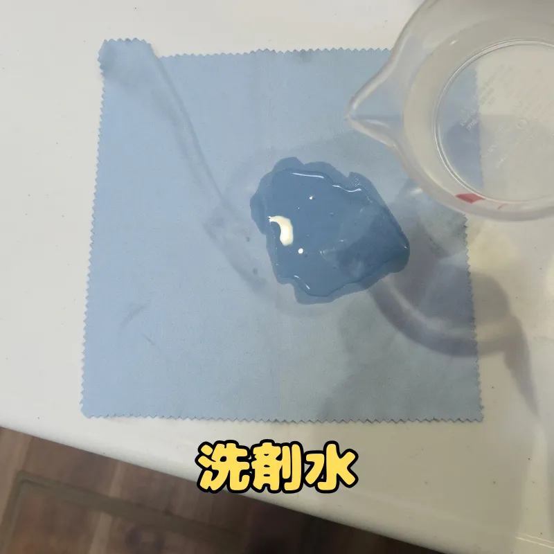 計量カップで作った中性洗剤の薄め液をクロスに含ませている様子。