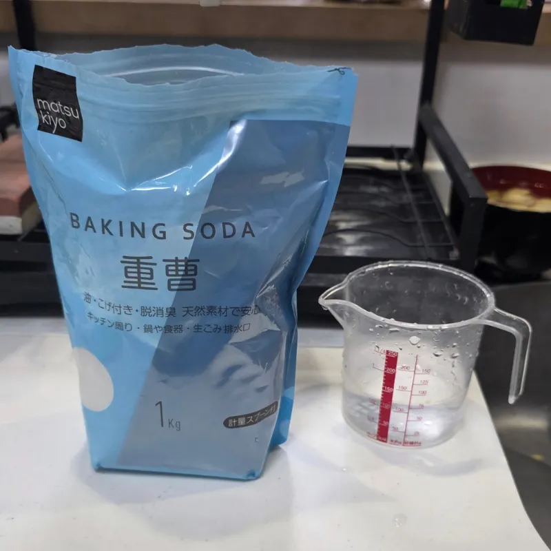 重曹水を作るために用意した重曹のパッケージと水が入った計量カップ。