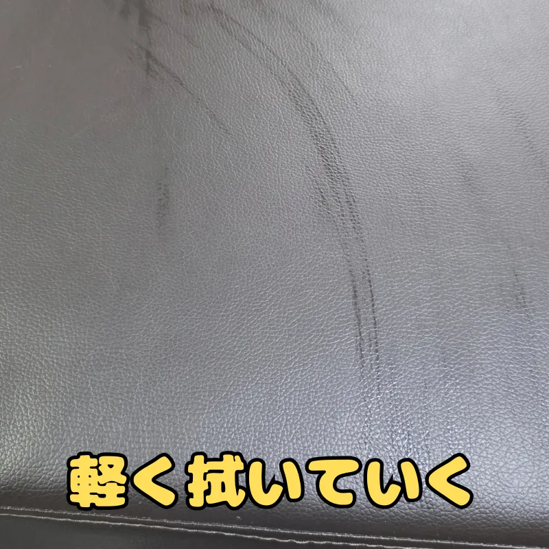 洗剤水を含ませたクロスで合皮ソファーの表面を優しく撫でるように拭いている様子。