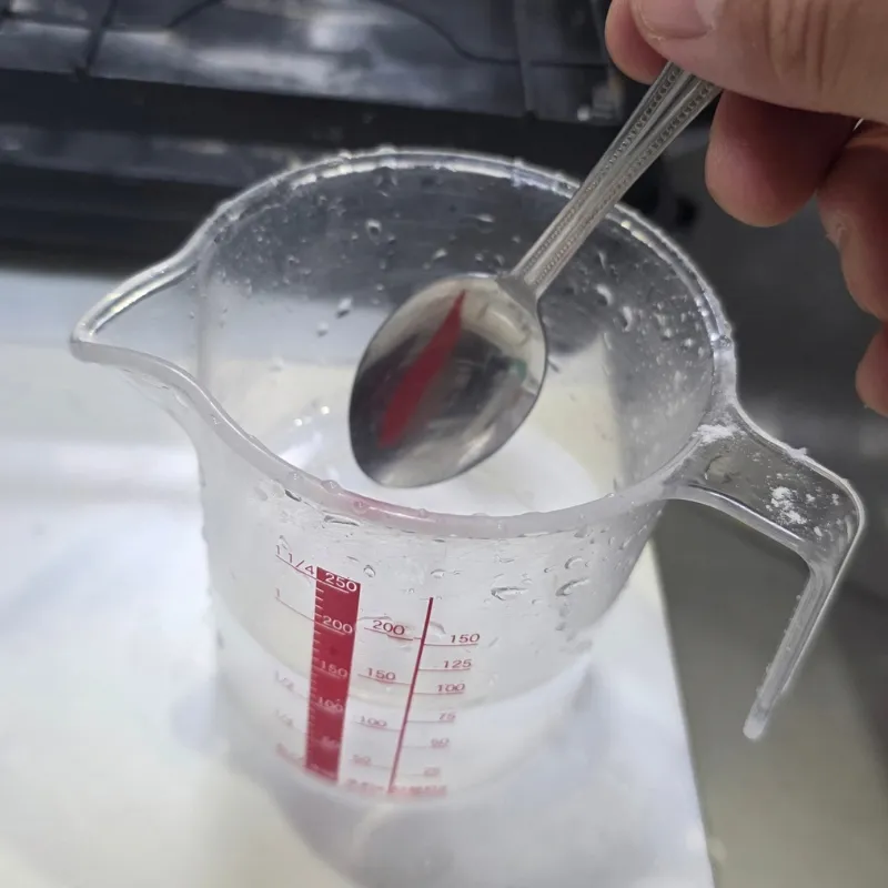 スプーンを使って重曹が溶けきるまでかき混ぜている状態。