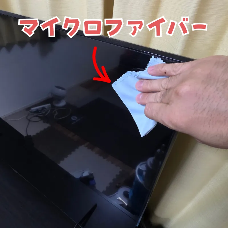 乾いたマイクロファイバークロスでテレビ画面を優しく拭いている様子。