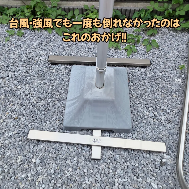 物干し台の接地面を広げて強風による転倒を防ぐ、コンクリートベースの底面に通されたアルミ製の転倒防止補助バー。