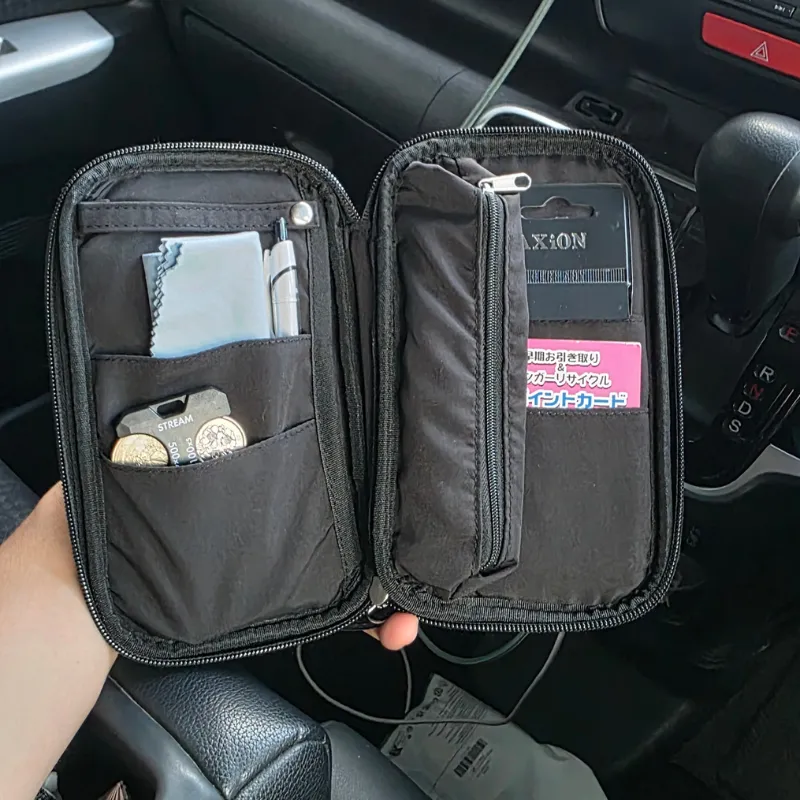 車内で開かれた黒いポーチの中に、予備のハンカチがペンや小銭などと一緒に収納されている様子。