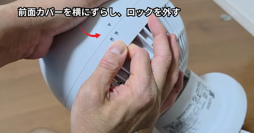 前面カバーの上部を両手で持ち、ガイドマークに合わせてカバーを横にスライドさせてロックを解除している様子。
