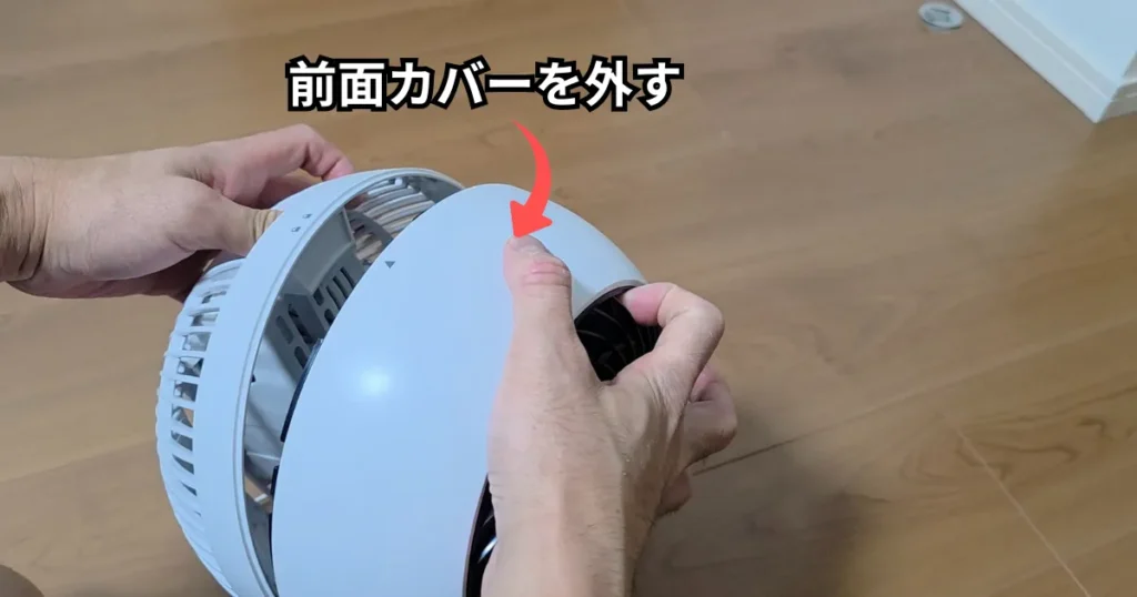 ロック解除された前面カバーを、両手でしっかりと保持しながら手前に引いて取り外している最中の様子。