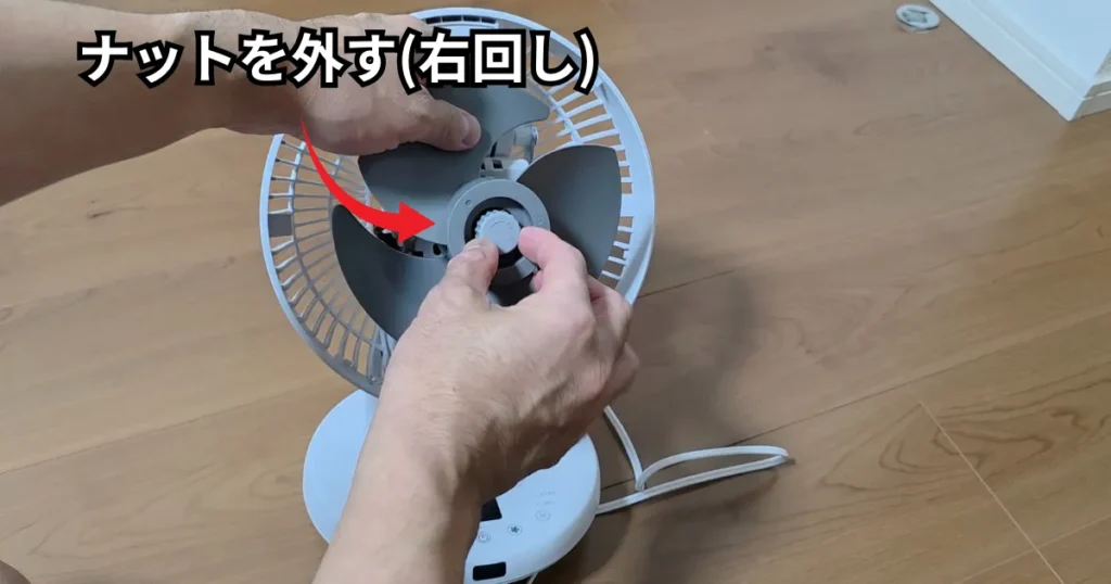プロペラが回らないよう片手で押さえながら、中央の固定ナットを逆ねじの仕様に合わせて右回しで取り外している様子。
