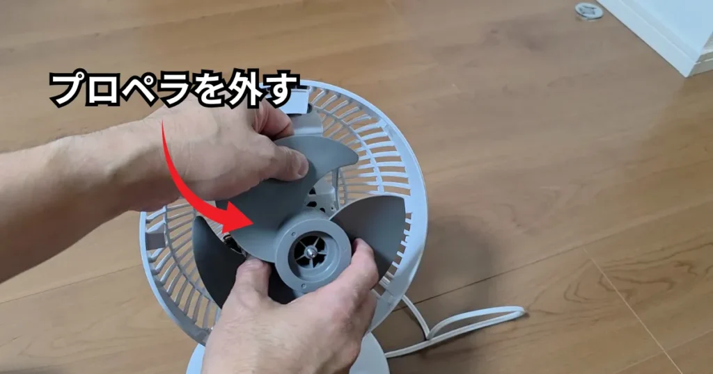 中央のナットを取り外した後、両手でプロペラをしっかりと持ち、モーター軸から手前へ真っ直ぐに引き抜いている様子。