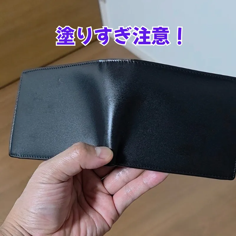 薄手の黒いビジネス財布にミンクオイルを塗りすぎたため、油分が浸透して全体がヨレヨレになり型崩れを起こしている状態。