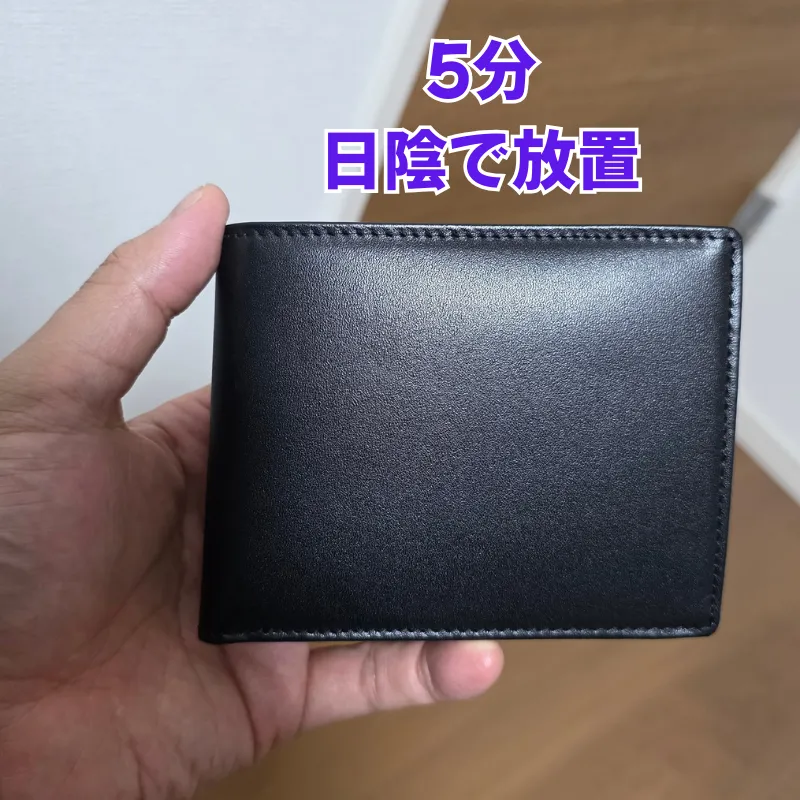 抗菌クリームを全体に塗り広げた後、革へ馴染ませるために5分ほど日陰で放置している黒い革財布。