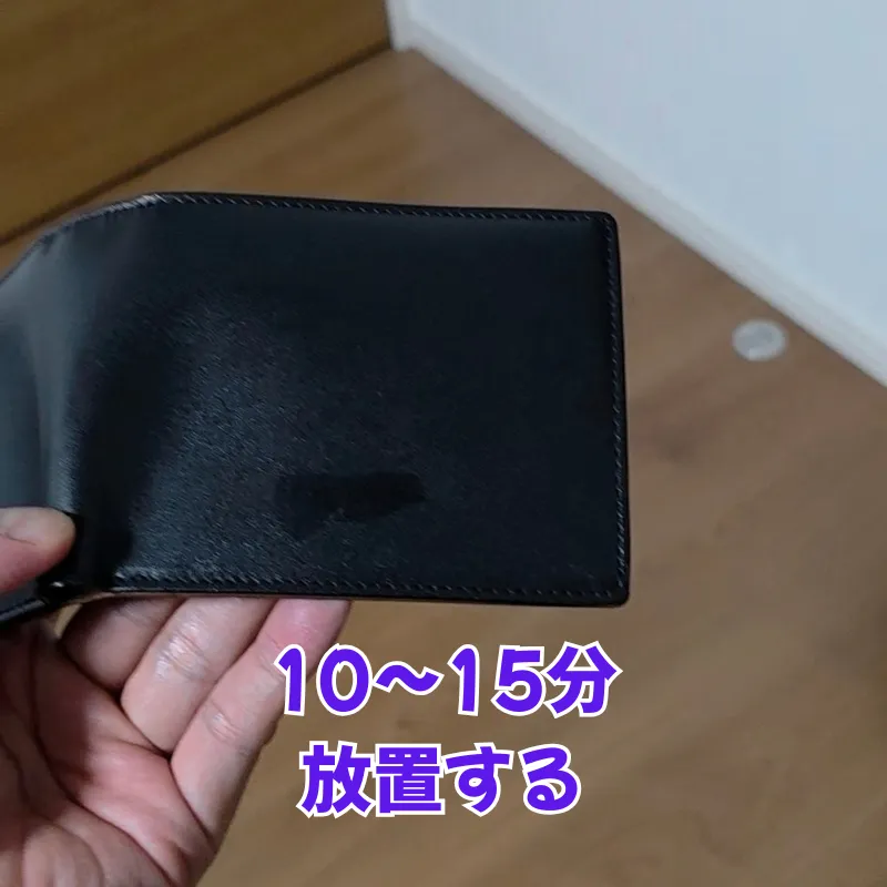 ミンクオイルを薄く塗り広げた後、油分が浸透しすぎるのを防ぐため、そのまま10分から15分ほど放置して馴染ませている黒い革財布。