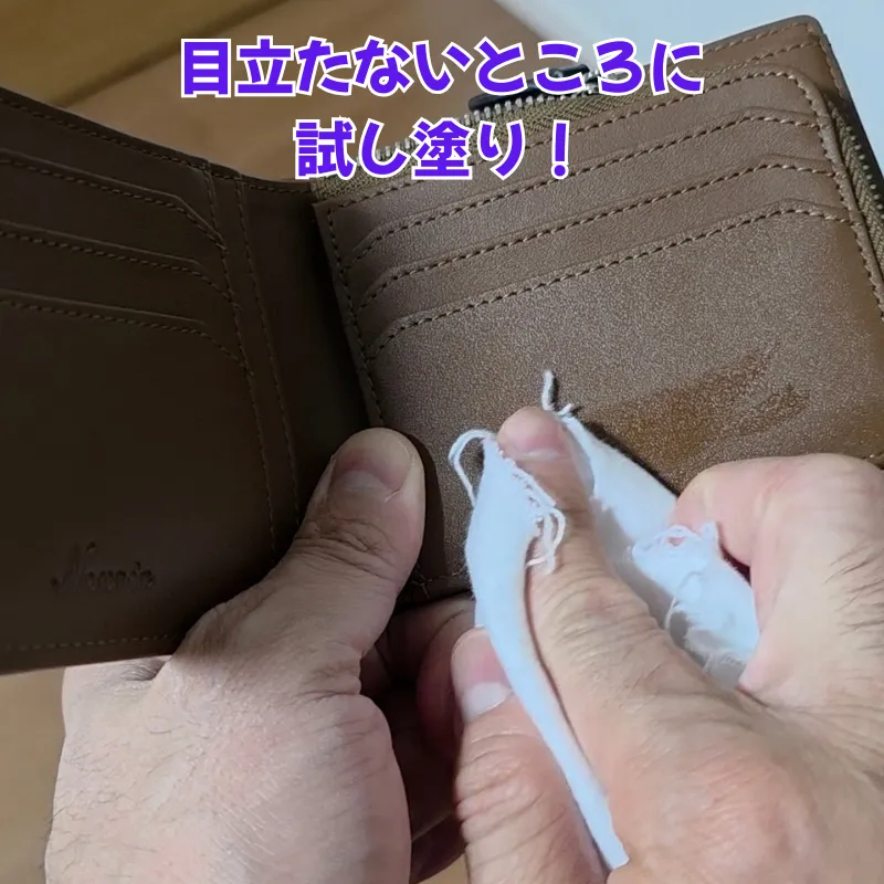 財布を開き、内側の目立たない部分に少量のミンクオイルを塗布してパッチテストを行っている様子。