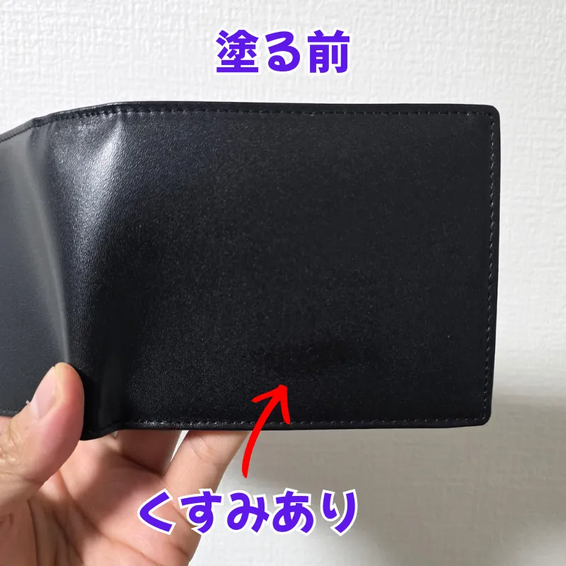 お手入れをする前の、下部に白っぽいくすみがあり全体的に乾燥している黒い革財布。