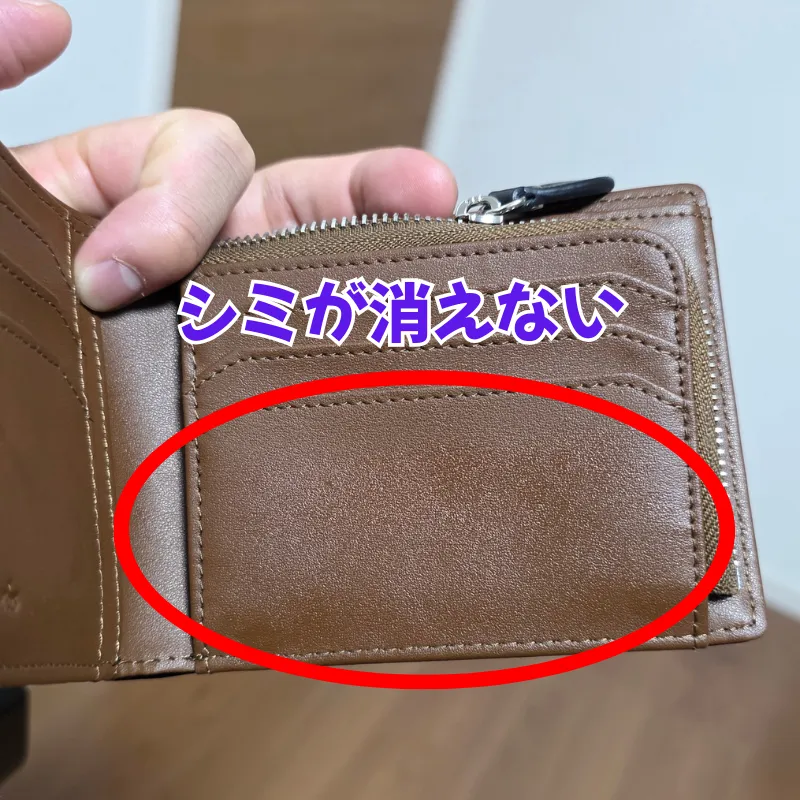 手で持たれた茶色い革財布の内側。カードポケット部分にシミが消えずに残ってしまった様子。