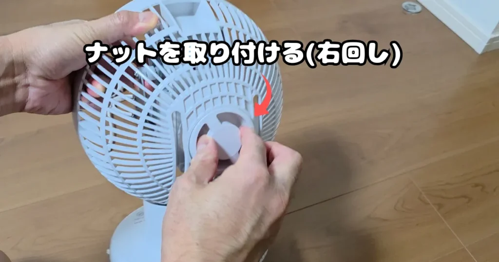 後面カバーをモーターにセットし、中央のガード固定ナットを右回しで締めて固定している様子。