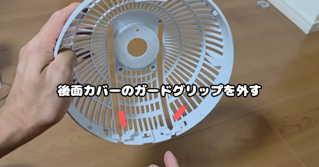 手に持った後面カバーの内側を向け、下部にある固定用のガードグリップを確認している様子。