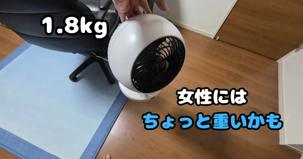 本体重量1.8kgのサーキュレーター背面の持ち手に指を掛けて片手で持ち上げている様子。女性には少し重く感じられる重量感である。