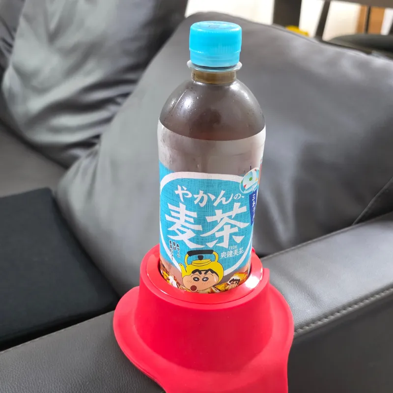 ソファの肘掛けに設置した赤いカウチコースターに、ペットボトル飲料がすっぽりと収まっている状態。