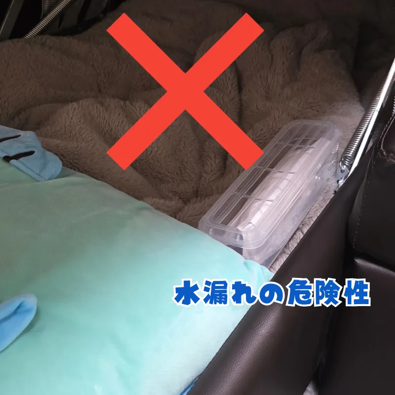 カウチソファの収納スペースに、毛布やクッションと一緒にタンク式の除湿剤が置かれている様子。