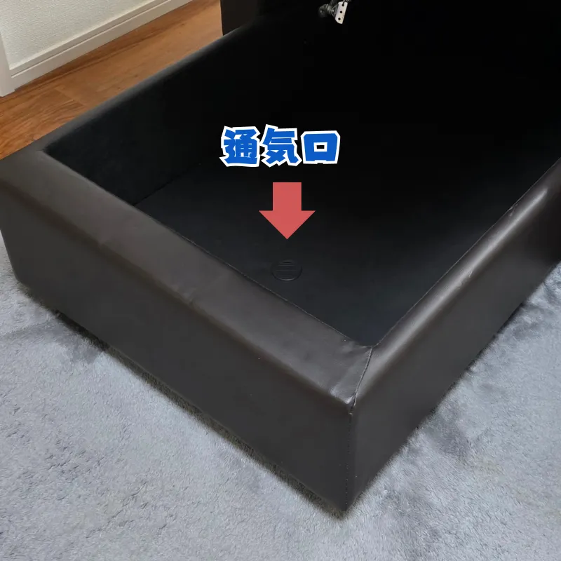 黒いカウチソファの座面下収納スペースの底面にある、丸い通気口。