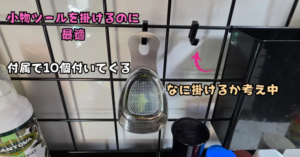 山崎実業(tower)のレンジフードメッシュパネルに取り付けられた2つの付属フック。片方にはステンレス製の小物ツールが掛けられている様子。