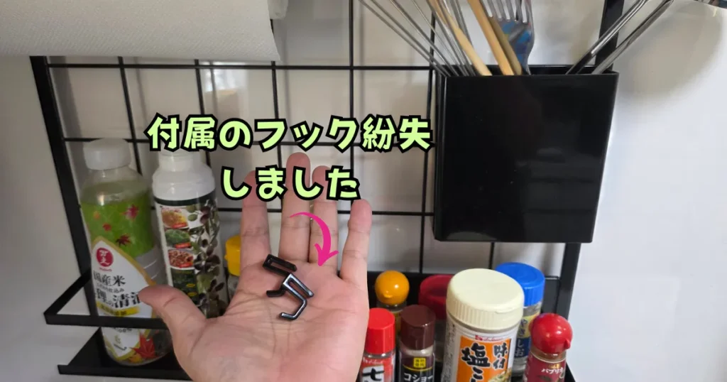 山崎実業(tower)のレンジフードメッシュパネル用の黒い付属フック。一部を紛失してしまい、残った2つのフックを手のひらに乗せている様子。