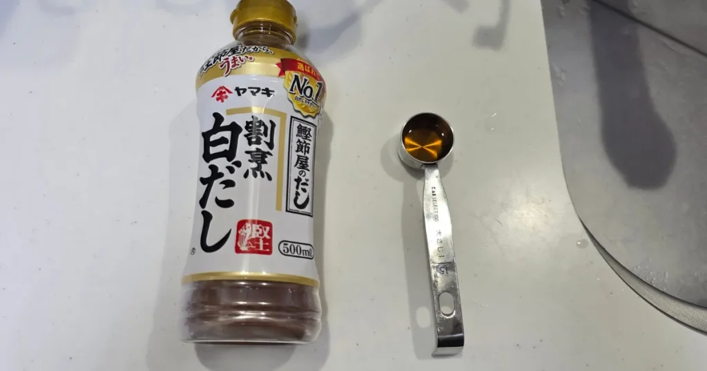 白だしのボトルの横に、白だしを入れた計量スプーンが置かれている。