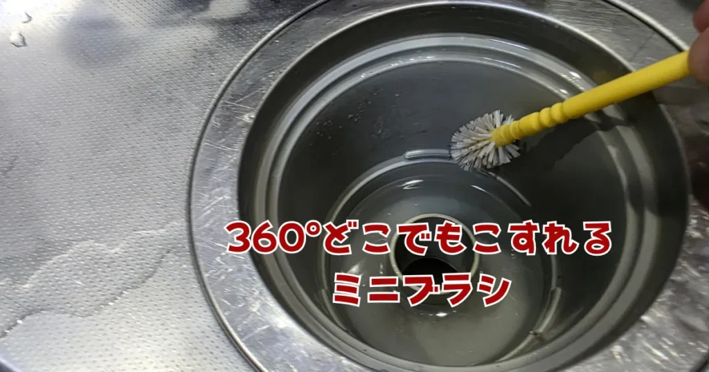 排水口内部の曲面や奥の配管部分を、全方位の汚れを落とせる黄色のミニブラシでこすり洗いしている様子。