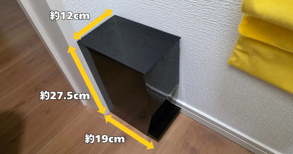 幅約12cm、高さ約27.5cm、奥行き約19cmのスリムなサイズの黒いtowerサニタリーボックスが、トイレの壁際にぴったりと収まっている様子。