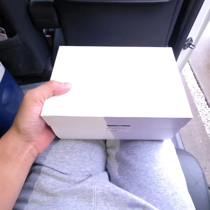 車の座席に座る同乗者の膝の上に置かれたケーキ箱。