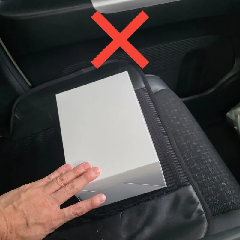 車の助手席に置いた白いケーキ箱を片手で押さえている状態。