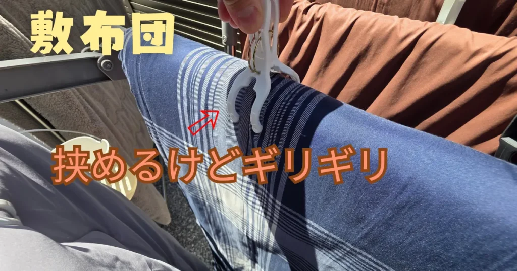 厚みのある敷布団をギリギリで挟んでいる大型の洗濯ピンチ。