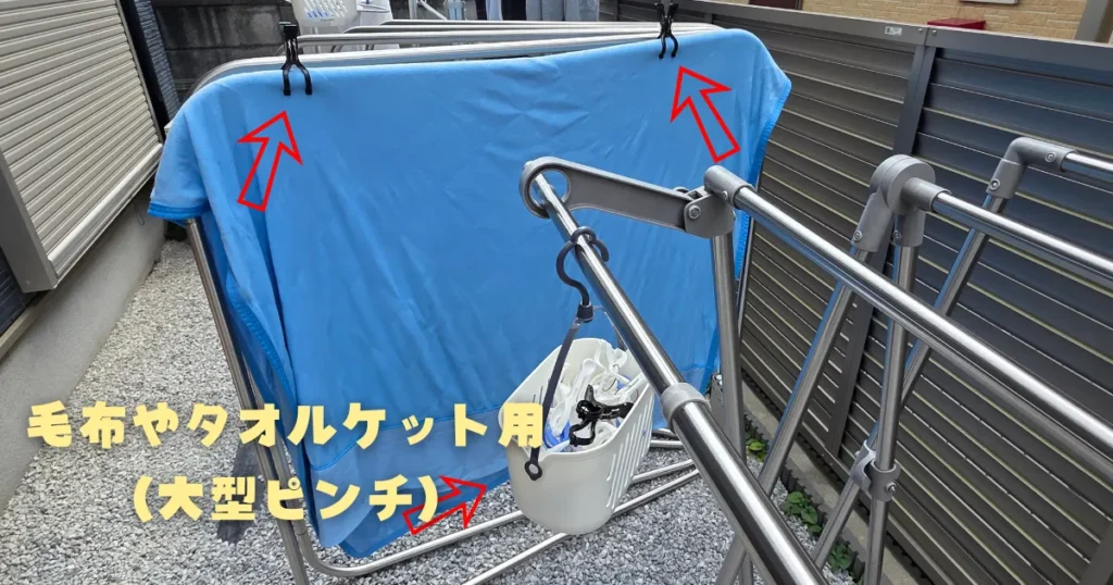 毛布やタオルケットを干している物干し竿の真横に掛けられた、大型ピンチ専用の収納カゴ。