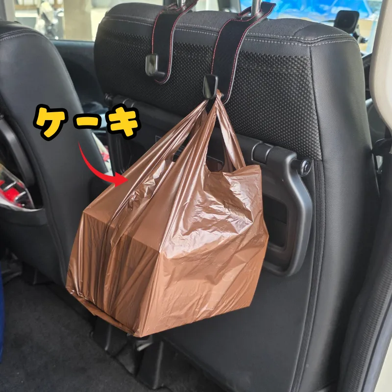 車のシートフックに掛けられたケーキの箱が入った袋。