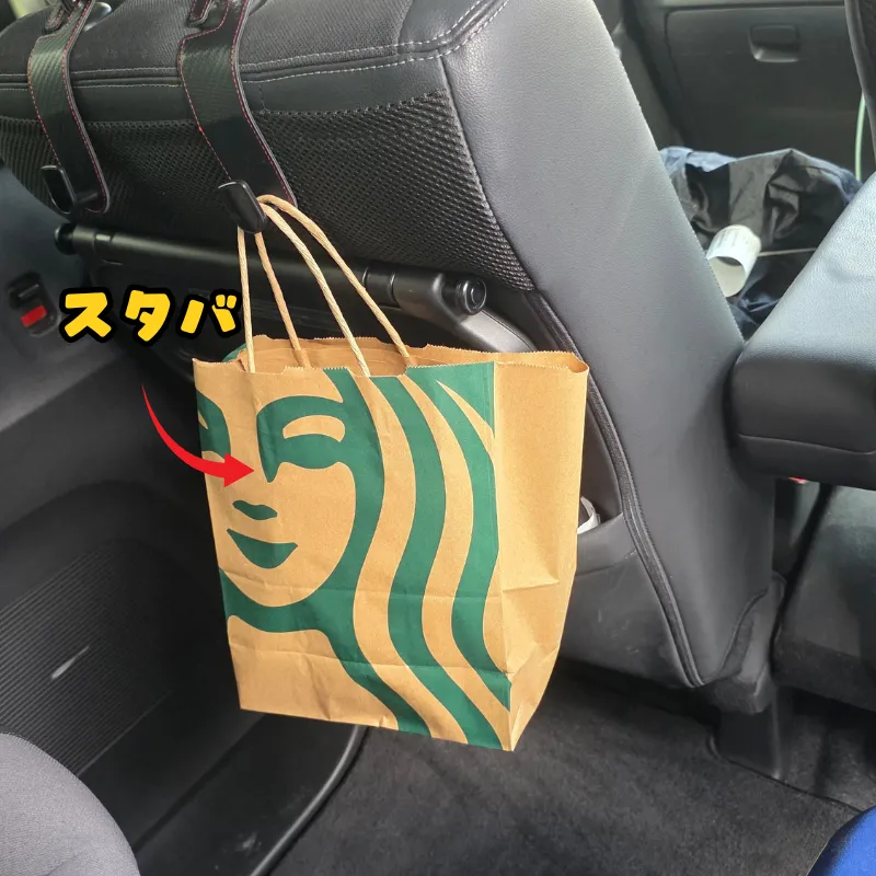 車のシートフックに掛けられたスターバックスのテイクアウト用紙袋。