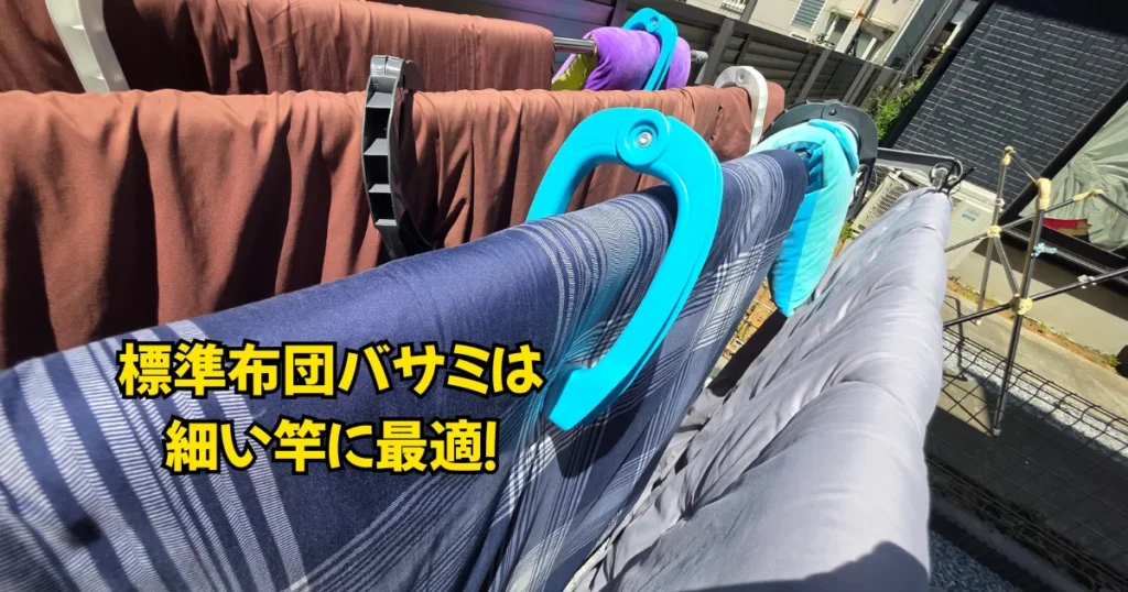 庭の細い干し竿に対し、標準サイズの布団バサミを使って布団を密着させ、ガッチリと固定している様子。
