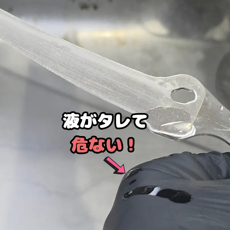 黒いゴム手袋にサビ取り剤の液がこぼれ落ちている様子。
