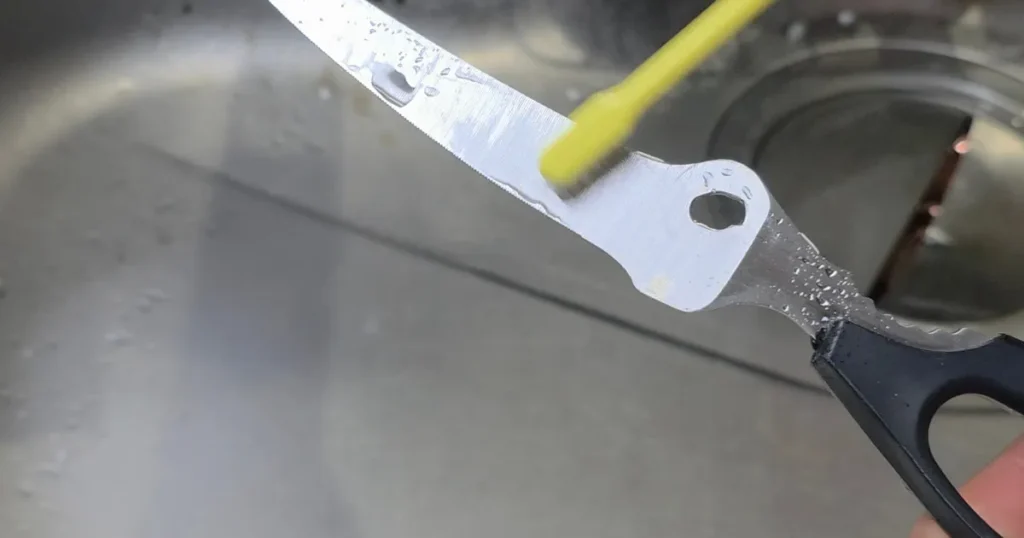 キッチンバサミに塗った重曹ペーストを歯ブラシでこすっている様子。