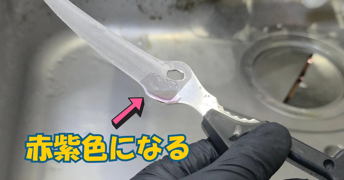 キッチンバサミの結合部に塗った透明なジェル状のサビ取り剤が、サビと反応して赤紫色に変色している様子。