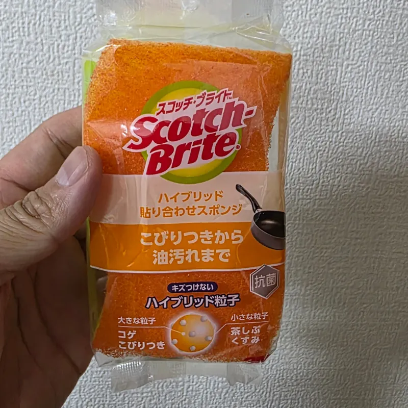 シンクに置かれた黒いシリコン製調理スプーンと、オレンジ色の波型スポンジが並んでいる様子。